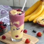 How to Make the Perfect Banana Berry Smoothie (Healthy, Easy & Delicious) 10 Glass of banana berry smoothie with fresh bananas, strawberries, and blueberries on the side
